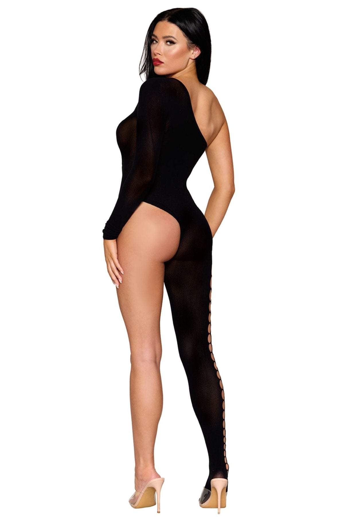 A person is modeling the One Leg Bodystocking with Side Cut Out, featuring a bold black asymmetrical design with semi-sheer fabric. The bodysuit has one long sleeve and a full leg on the left side, adorned with multiple cut-outs running down the leg. The individual complements their look with beige high heels and has long, dark hair.